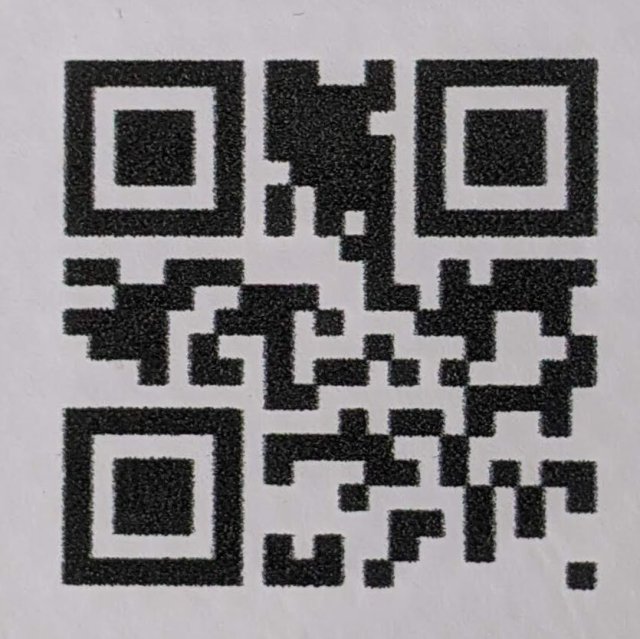 A photo of a Version-1 QR code with a very noticeable black area between the two alignment patterns in the top.