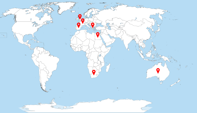 Map of the world showing the sea in blue and countries in white with black borders.  No countries are named.  There are red pins in a number of places around the world