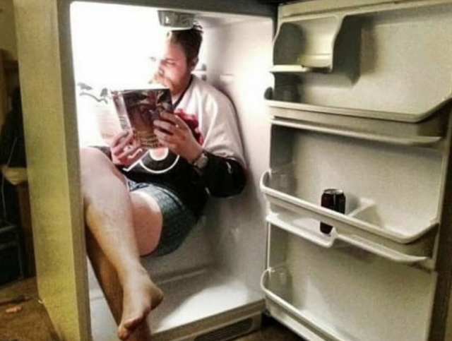 Someone sitting in a refrigerator reading a book. 