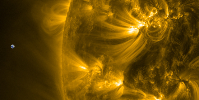 Ein extremer Zoom auf den linken Rand der Sonne. Da schießen Strahlenbündel von gleißend hellen Flecken weit ins All. Links die Erde vom Durchmesser her 110 Mal kleiner als die Sonne. 