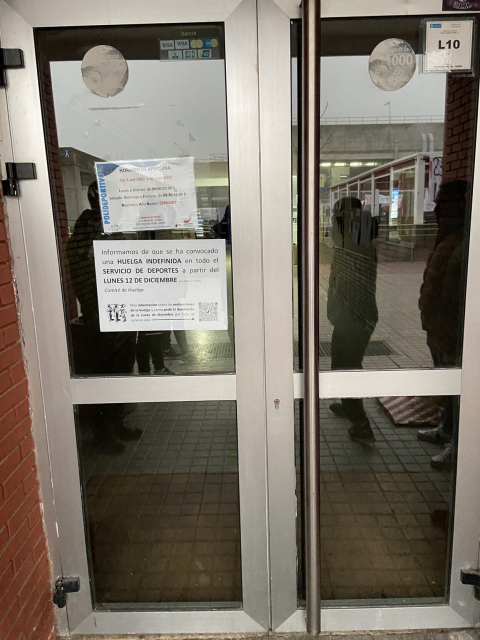 Puerta del polideportivo de la UAM. Debajo del cartel con los horarios otro cartel dice:
"Informamos de que se ha convocado una HUELGA INDEFINIDA en todo el SERVICIO DE DEPORTES a partir del LUNES 12 DE DICIEMBRE
Comité de huelga”