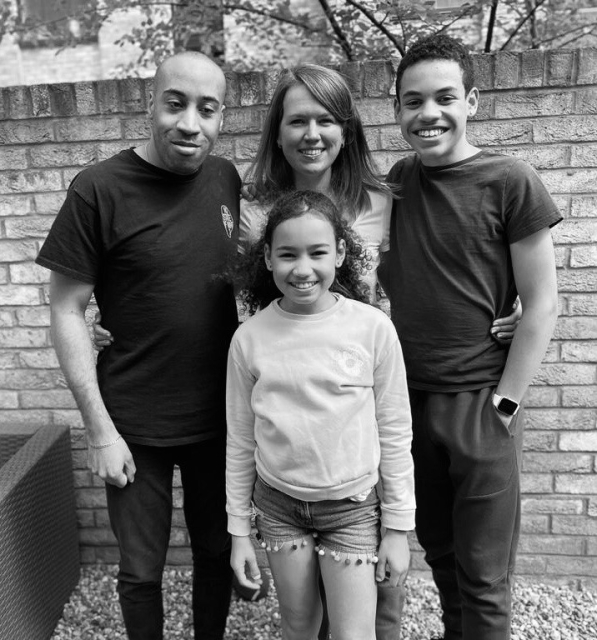Black and white picture. Andre stands on the left, Kirsten in the middle, Jake on the right and Alice in front. All smile towards the camera. 