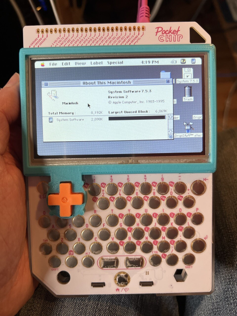 My hand holding a Pocket Chip with MacOS System 7.5.3 displayed on the screen with the About this Macintosh window open. 