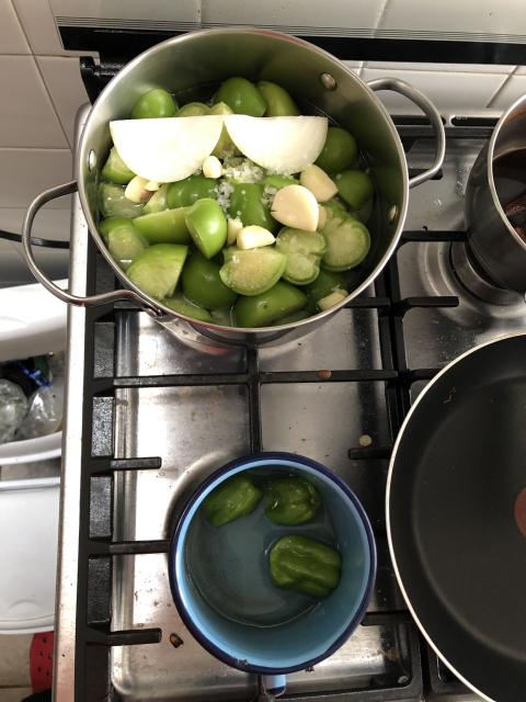 Olla con tomates verdes, cebolla y ajo; pocillo con chiles habaneros. Los cuezo por separado porque los niños quieren salsa sin chile.