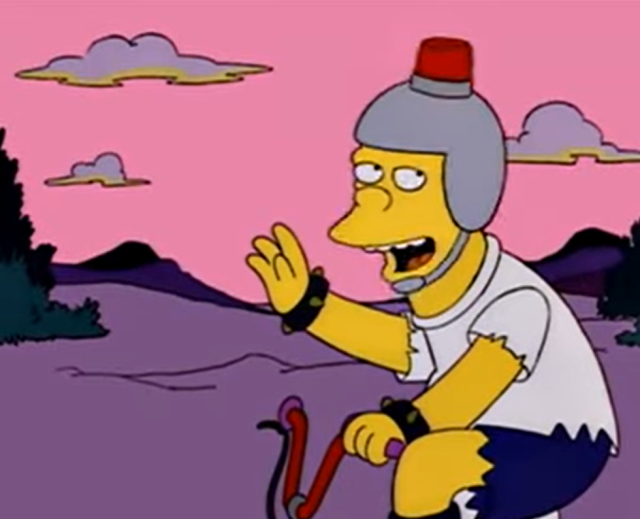 Fotograma de Los Simpsons en los que se ve un adolescente en bicicleta con un casco en el que lleva una luz de emergencia simulando ser la policía.