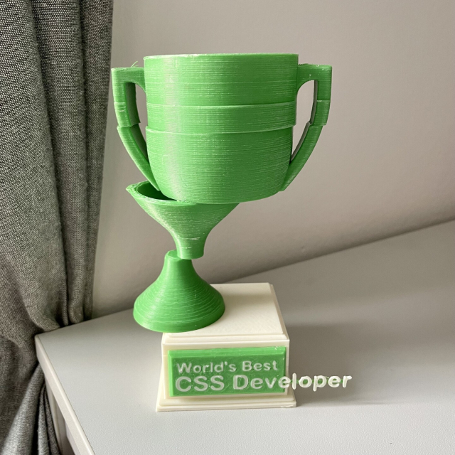 Zelený pohár rozdělený na jednotlivé posunuté části s vytékajícím textem “World´s best CSS developer”