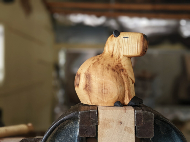 Capybara dodu en bois, posture assise, yeux clos, serein