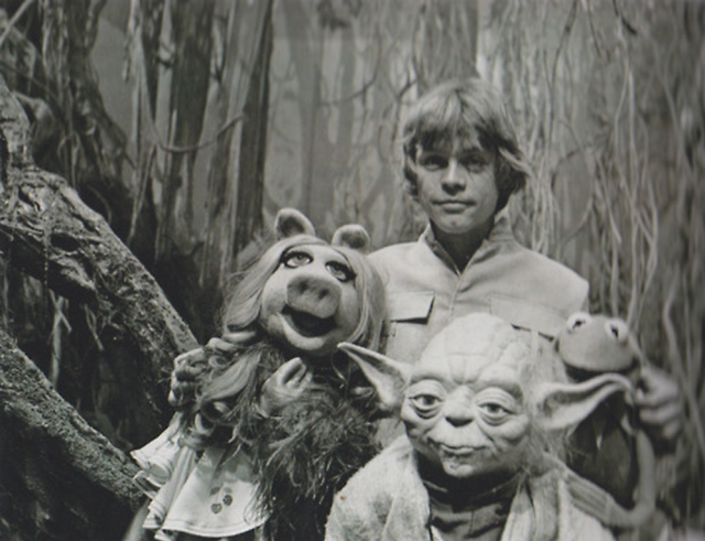 Black and white picture of Luke Skywalker, Yoda, Miss Piggy and Kermit the frog all posing together. 