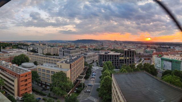 Sunset view of a Prague city center with a castle and Petřín hill in the far background