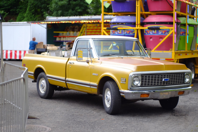 A yellow pickup truck in a vintage style, but well maintained.