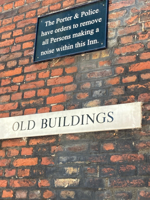 a sign that says "Old Buildings" below another sign that says "the Porter & Police have orders to remove all Persons making a noise within this Inn."