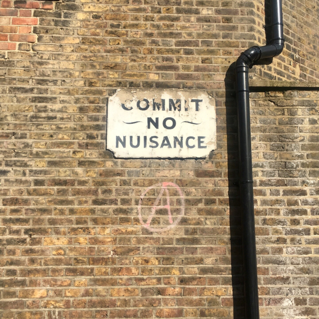 A sign on an old brick wall that says “COMMIT NO NUISANCE” in an old-fashioned sans serif font