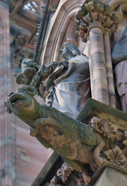 stylised mutton below several clothed figures. above a tiny naked beared figure with a pointy hat - Jews were depicted like that in medieval times.