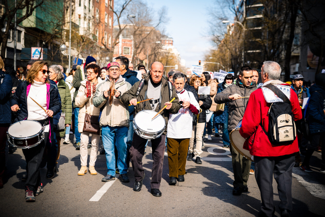 Foto en plano general de un grupo de músicos (tambores, saxos, platillos y panderetas) tocando una marcha. Columna este de la Manifestación por la Sanidad en Madrid que sale desde el Hospital de La Princesa.