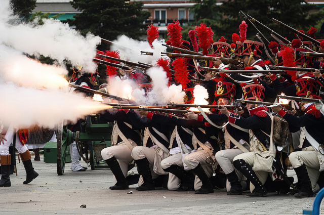 Recreaciones del Dos de Mayo en la Plaza de Oriente en Madrid. 

Imagen en la que se ve a un destacamento de tropas napoleónicas descargando sus rifles. Se ve la ristra de pólvora y la chispa ardiendo de los rifles.