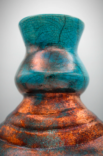 A close up of the neck of a raku pottery vase.