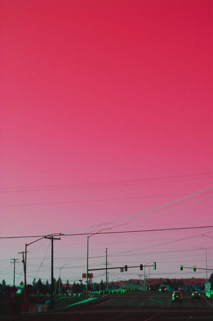 Pale red sky with gree streets and telephone poles 
