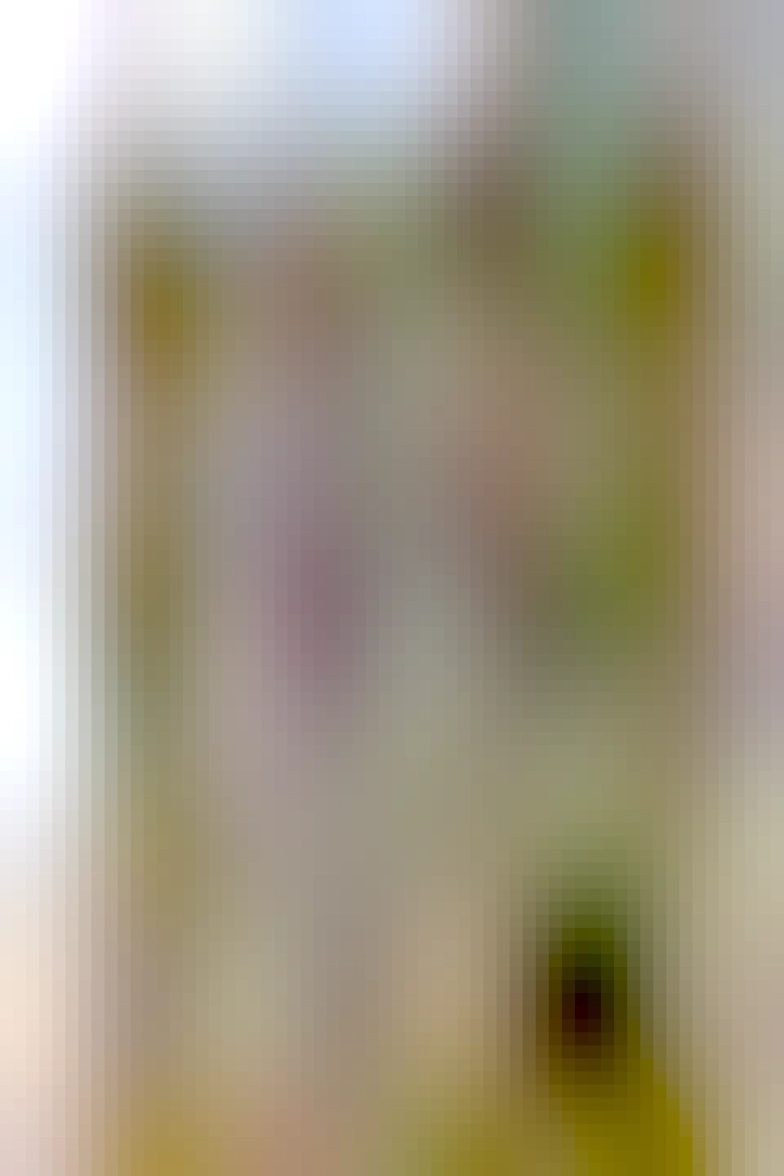 A colour photograph of a ruined castle exterior. The sky is blue behind the building and the structure is built from light coloured tightly packed stone. A door and arrow loops are visible and golden grass grows around it. 