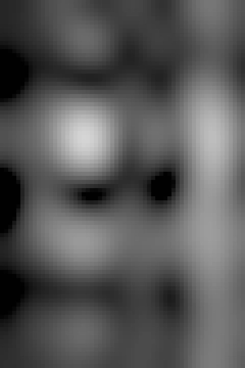 A black and white photograph of a ruined castle interior. A set of stone steps lead up to a window with tightly packed stone walls all around it. 