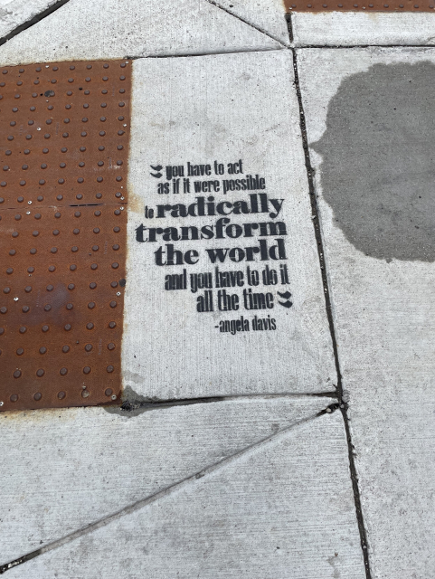graffiti on the sidewalk says “you have to act as if it were possible to radically transform the world and you have to do it all the time” angela davis