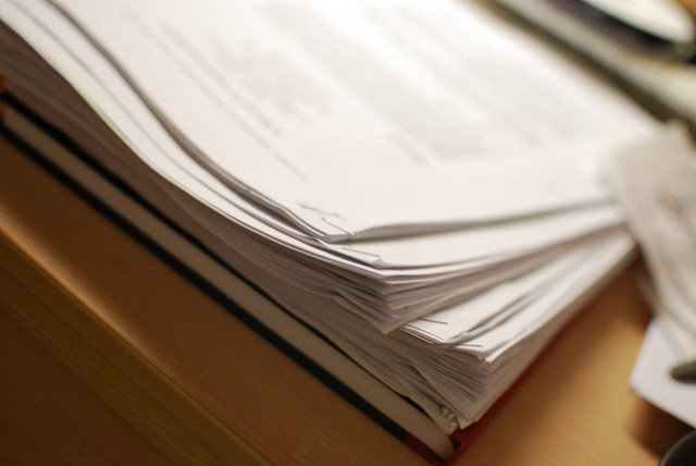 Photo of a stack of papers on a wooden desk