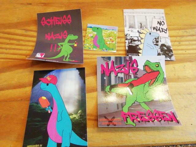 Knuffige Dinosticker mit Aufschriften wie "Nazis Fressen" und "No War".