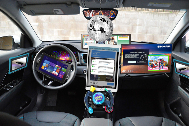 A vehicle interior covered in a comical amount of distractions. There's a windows 8 tablet on the steering wheel, the center column is an ipad with youtube covered by a "click on all images with roads" captcha covered by a cookie consent popover, with a notification at the top reading "Battery combustion likely. Tap for more infor...". There's a stretched tablet above the dash with some amazon products on it, and a sharp 4k television over the passenger side of the dashboard, with a turkey mode notification and a PIP video of lazytown. The door handles are those bulgy kids tablets with pictures of door handles on them, and the shifter is a bop it. The rear view mirror is showing a feed of basketball and there's a disco ball in front of it
