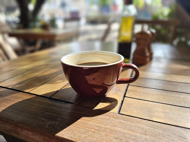 hnedá šálka čiernej kávy, na drevenom stole