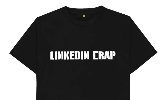White on black T-shirt. It looks like the band Linkin Park's logo, but it reads "LinkedIn Crap".