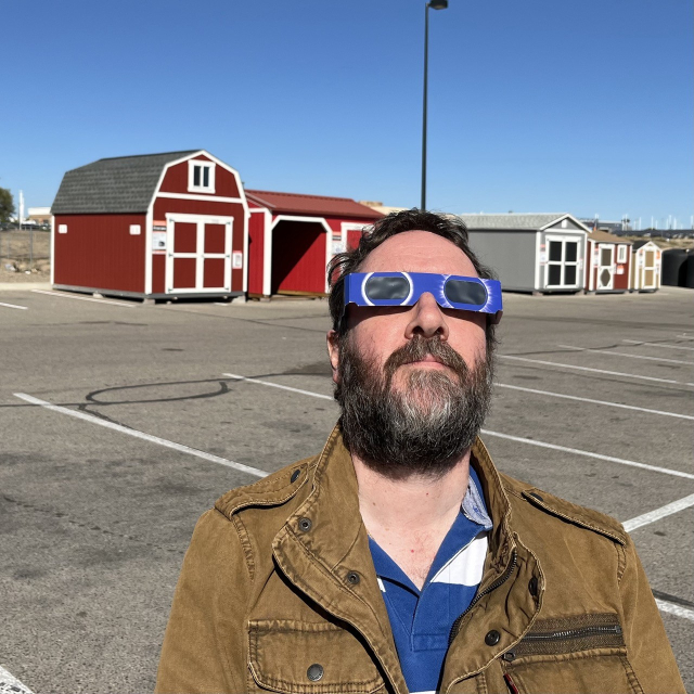 Man in solar glasses standing in a car park looking up