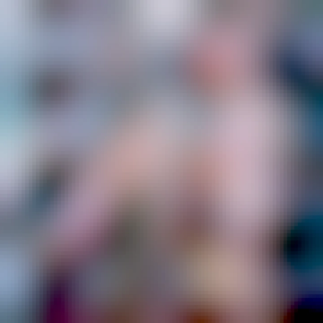 A pretty blonde woman sitting on the floor of a library, reading a book. She has her shoes off and is wearing pale nylons.