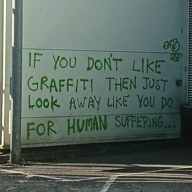 You can see a white house wall on which "if you don't like graffiti then just look away like you do for human suffering......" is written in green.