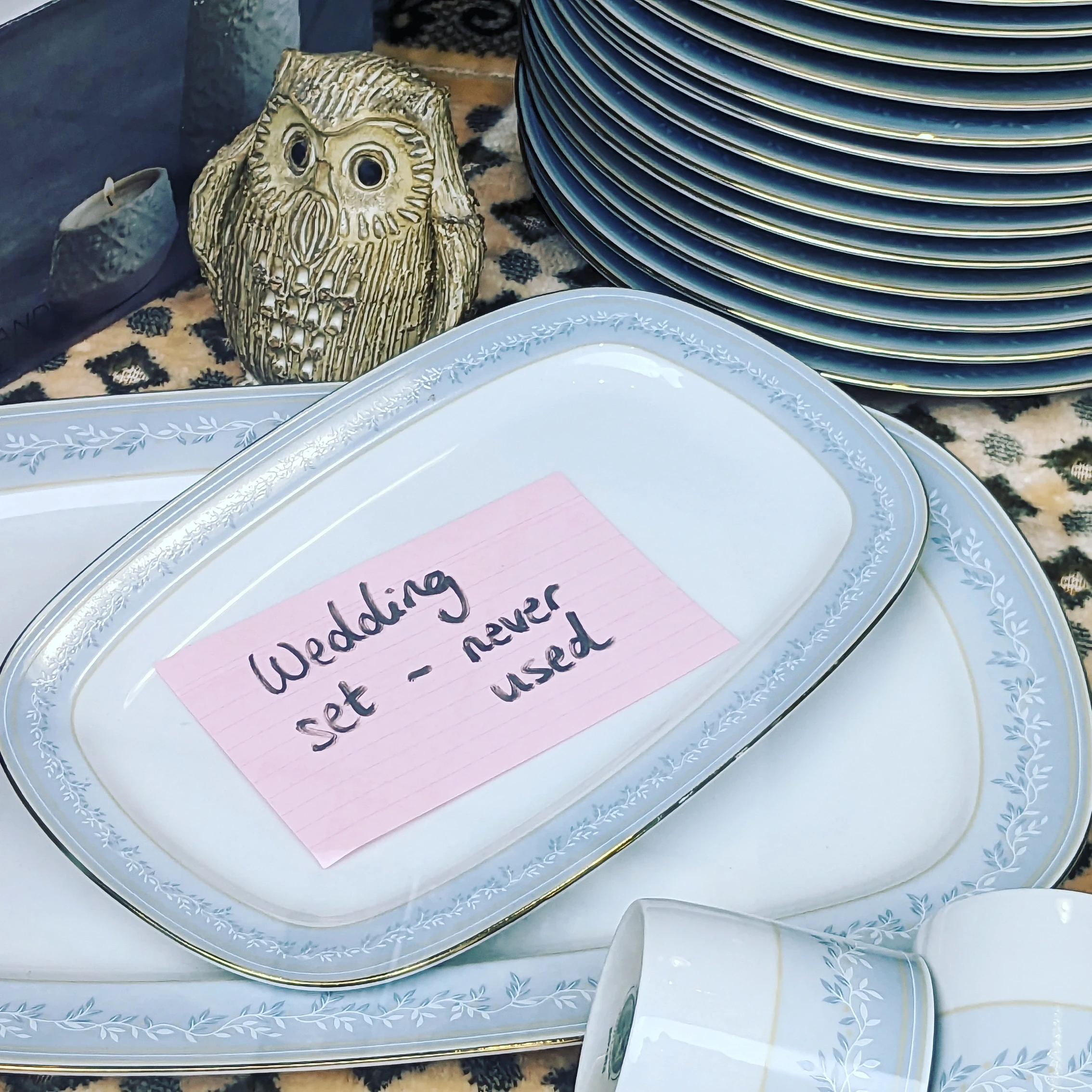 A set of crockery in a shop window with WEDDING SET - NEVER USED written on it.