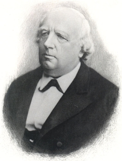 Black and white photo of Karl Weierstrass in his later years. His white hair is receding, longer in the back, and he is wearing a dark suit with a white collared shirt underneath.
