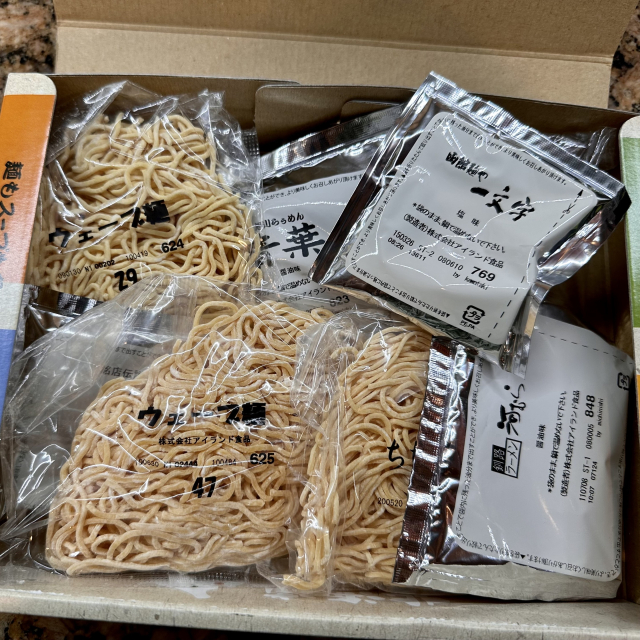 A box of four packs of noodles in packets, and four packs of soups
