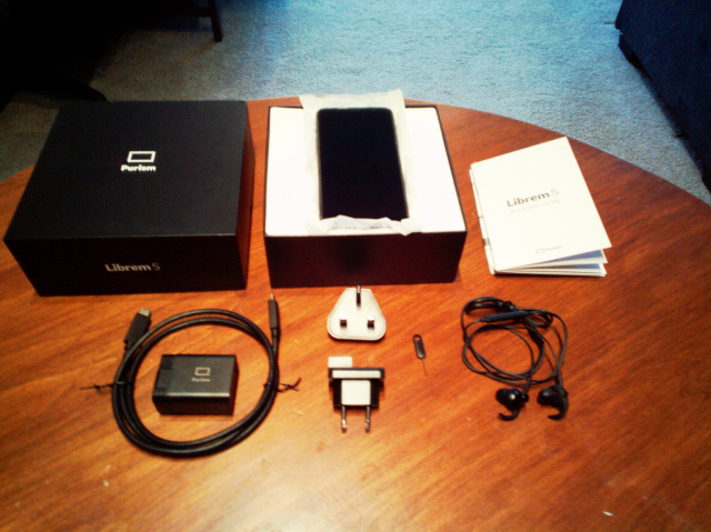 Librem 5 in box, with the included quick start guide, earbuds, SIM tool, power adapter (with included international plugs), and USB-C cable