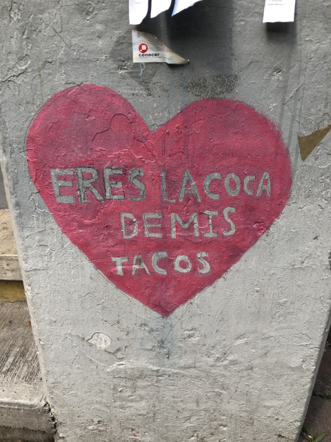 Un corazón rosa pintado sobre el concreto; adentro dice "eres la coca de mis tacos".