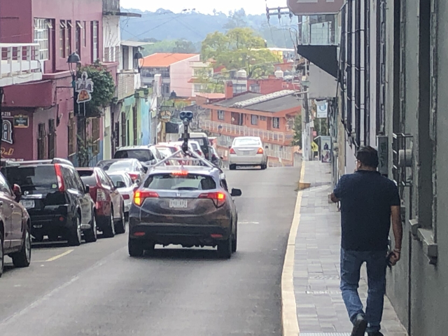 El coche de Street View, con su armatoste de cámaras sobre el techo. Va por una calle de bajada.
