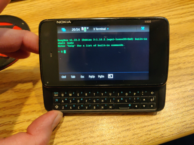 An old smartphone in landscape mode, with a slide out keyboard, running a linux terminal.