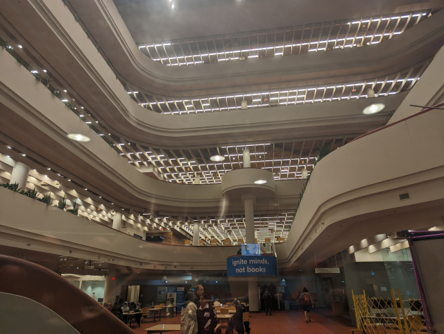 The grand, modernist atrium of Toronto's Metro Reference Library with a banner reading "IGNITE MINDS NOT BOOKS"
