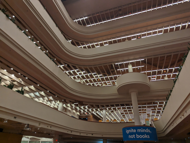 
The grand, modernist atrium of Toronto's Metro Reference Library with a banner reading "IGNITE MINDS NOT BOOKS"