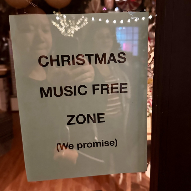 A sign outside a shop that says this is a Christmas music free zone, we promise