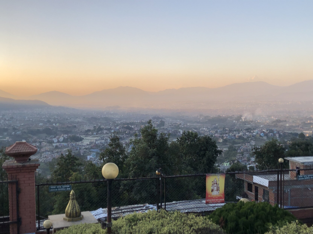 Kathmandu valley in the late afternoon, bathed in golden light. We are seeing it from the park on the hill around the statue of Lord Shiva.