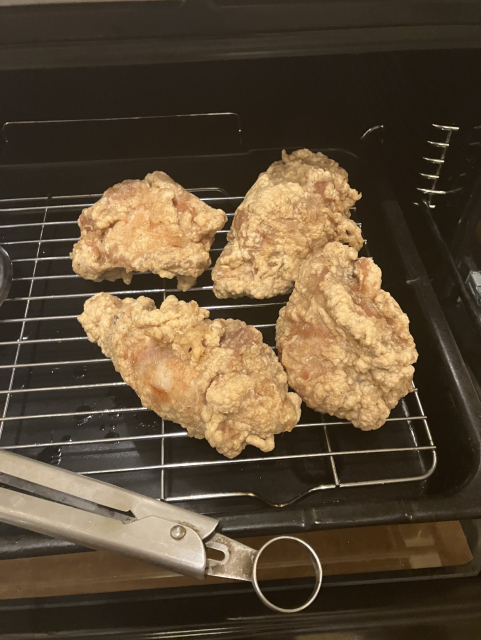 Four chicken thighs, coated in batter, after their first round of deep frying at 170C
