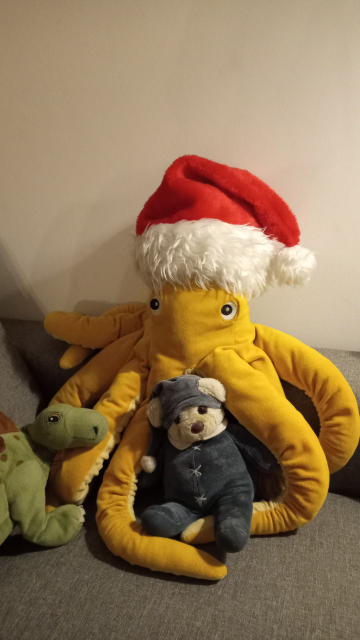 An octpus plushie with a christmas hat. There's also a plush dinosaur and a teddy bear.