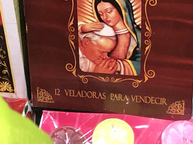 Caja de "12 veladoras para vendecir" (sic), con una imagen de la Virgen de Gudalupe haciéndole arrumacos a Juan Pablo II.