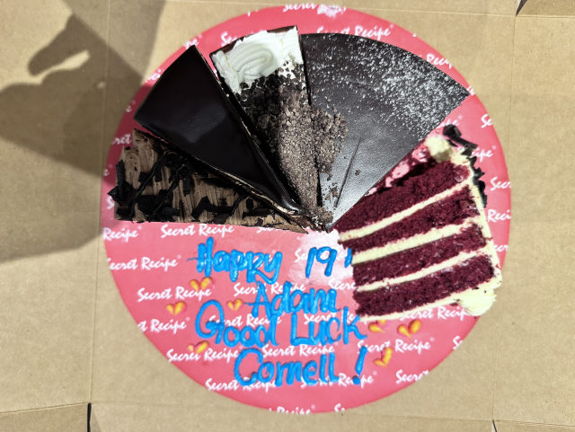 Assorted cake slices with a "Happy 19, Adam, Good Luck Cornell" message on the box.