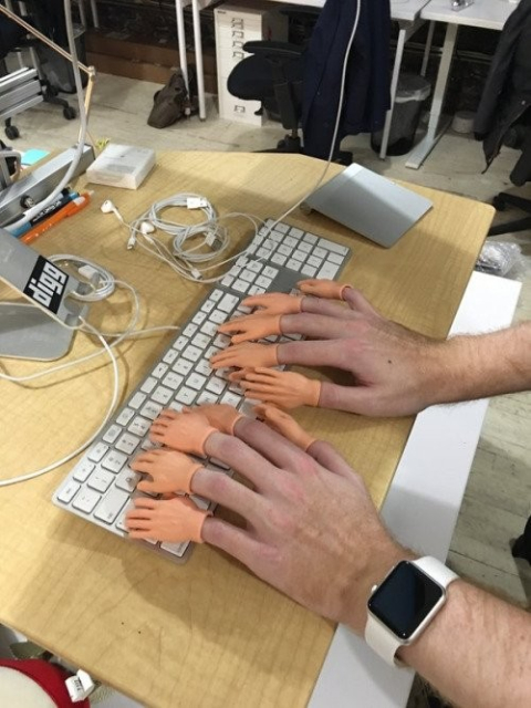hands on a keyboard with tiny finger plastic hand extension on each finger, so 10x "hands"