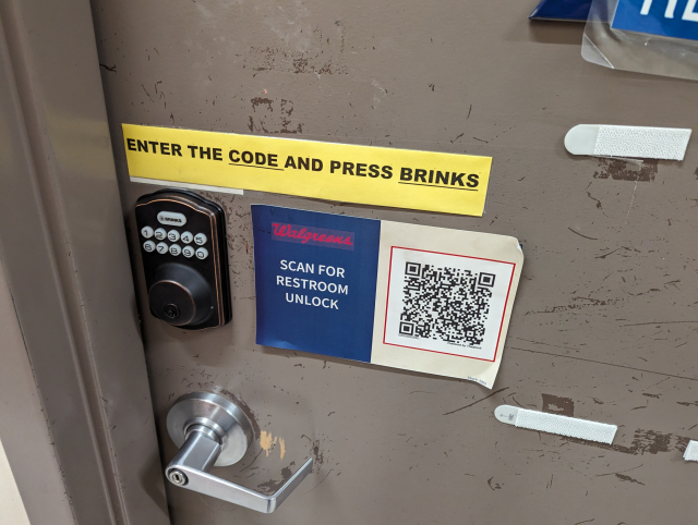 A bathroom door at Walgreens with a sign next to a QR code: scan for restroom unlock