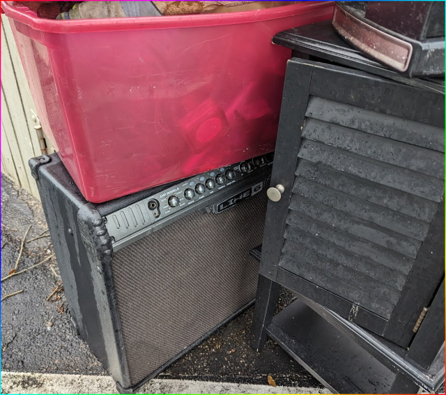 a guitar amplifier in the rain by the dumpster